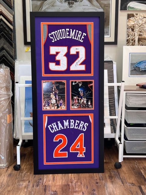 Framed basketball jersey display with blue-and-orange “Stoudemire 32” and “Chambers 24” on a floor stand