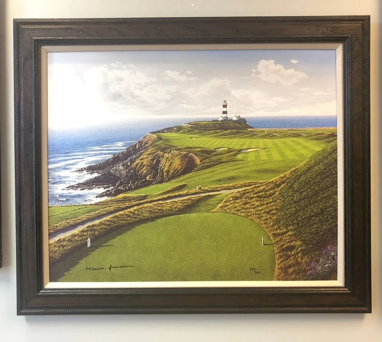 Framed coastal landscape painting with a lighthouse on a green cliff by the sea