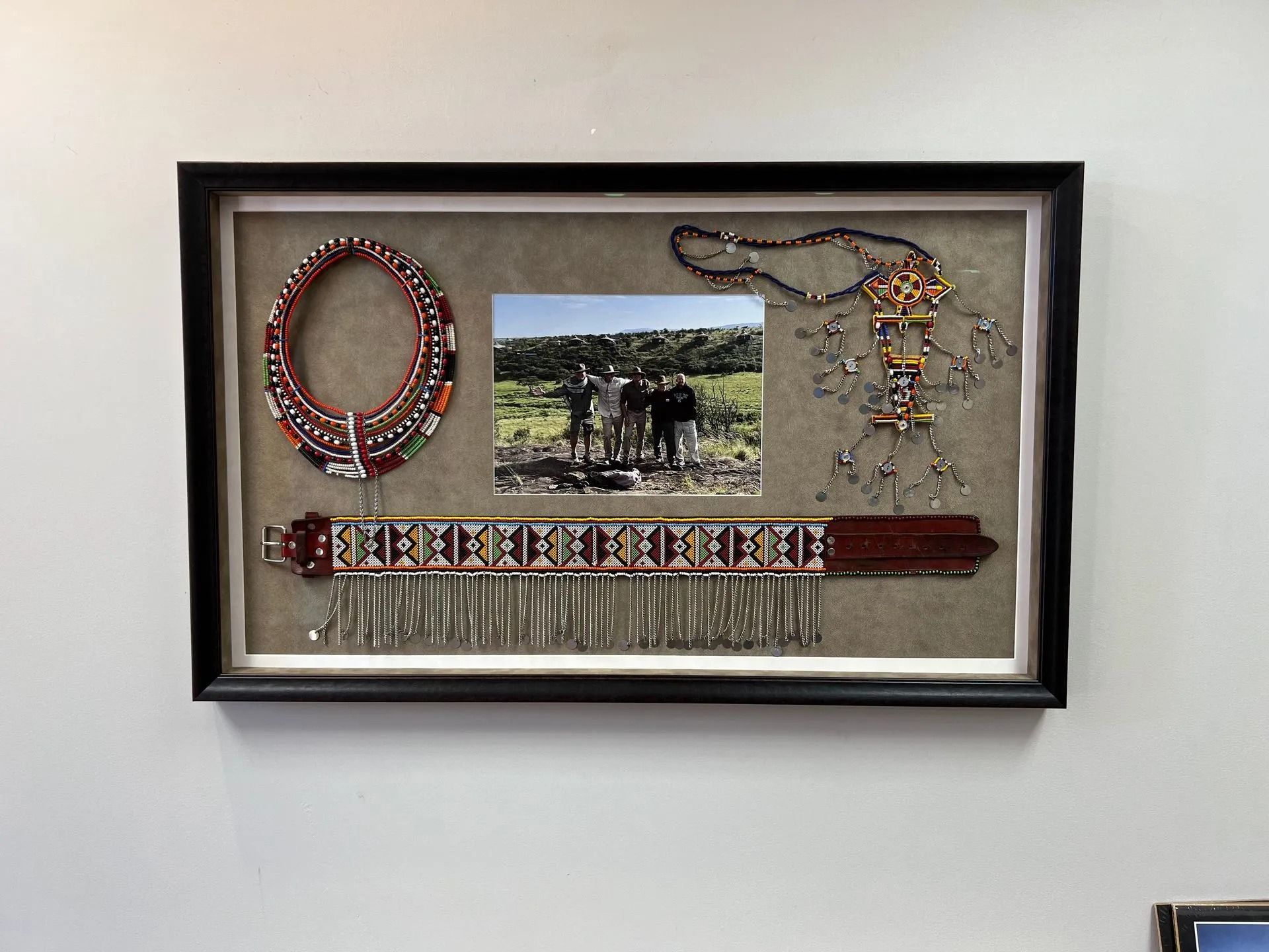 Framed handmade beaded jewelry display with necklace, bracelet, and ring around a small photo.