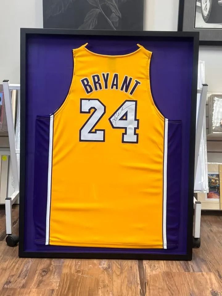 Framed yellow and purple Lakers basketball jersey with “BRYANT” and number 24.