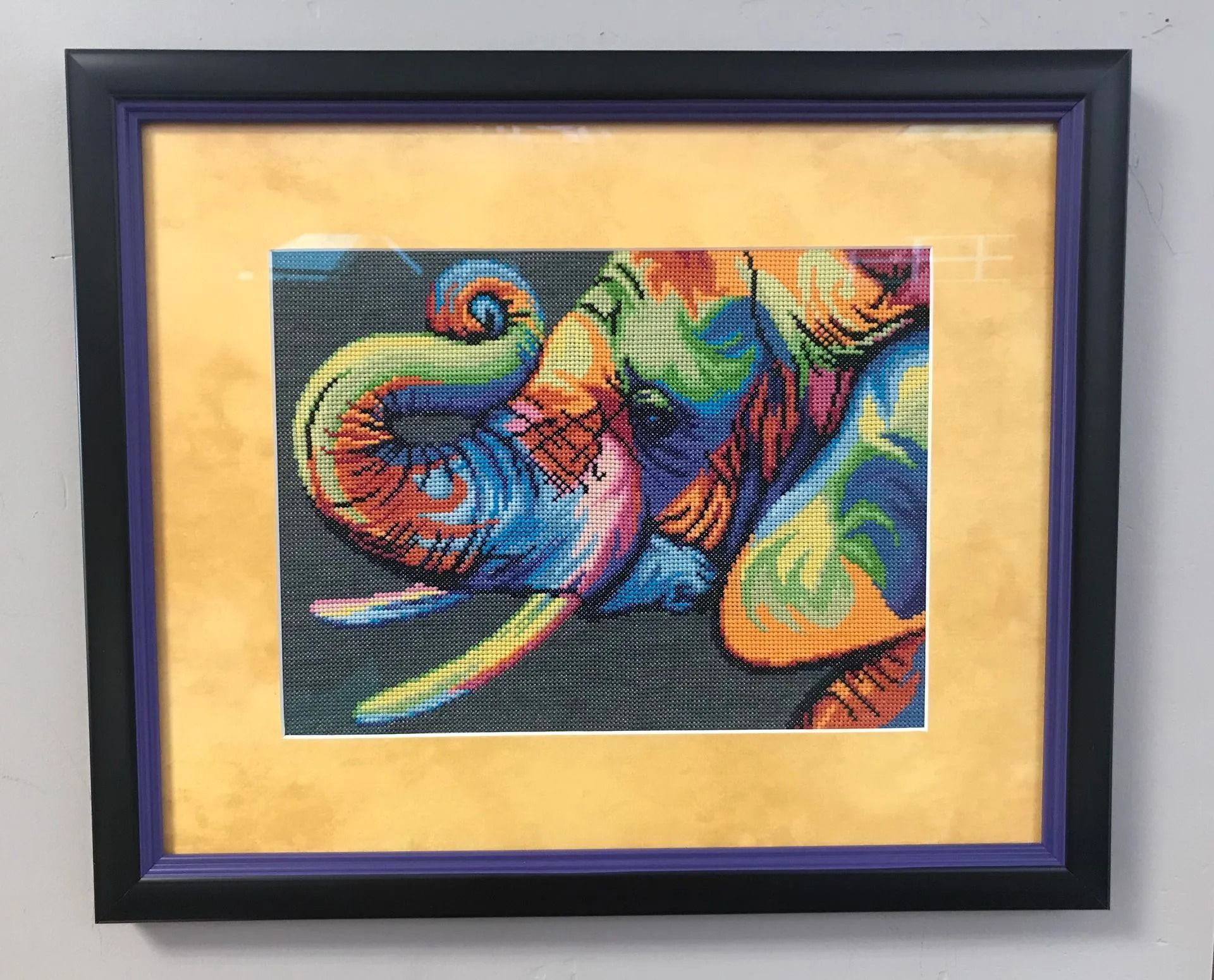 Framed colorful abstract painting with swirling blue, green, red, and yellow shapes on a beige mat