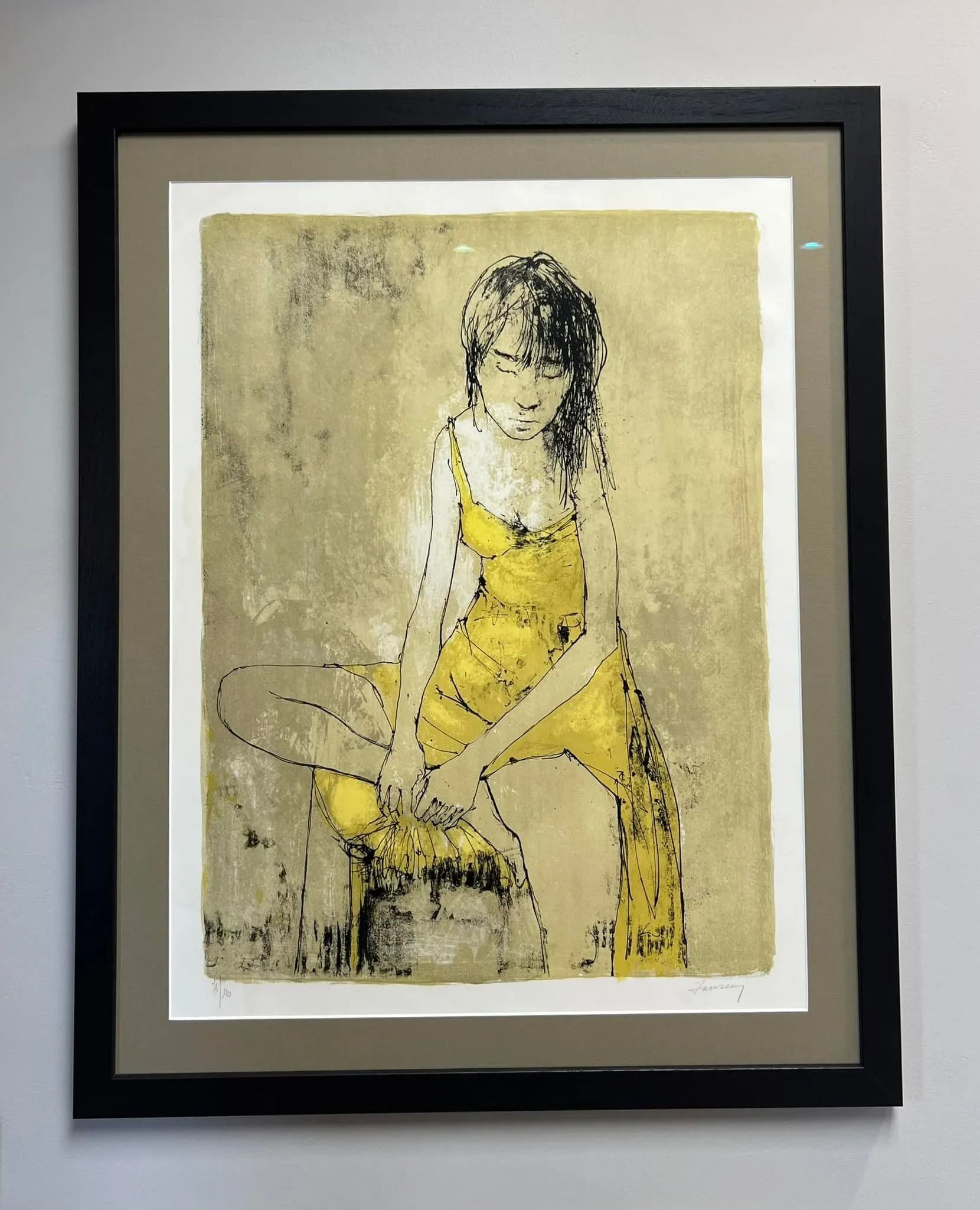 Abstract yellow and black figure artwork in a black frame on a light wall