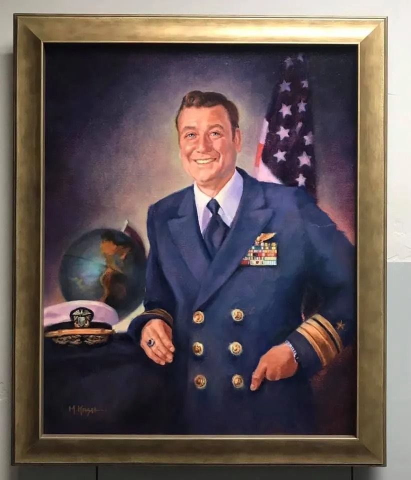 Portrait of a smiling uniformed man beside a globe and U.S. flag, wearing medals and gold cuffs