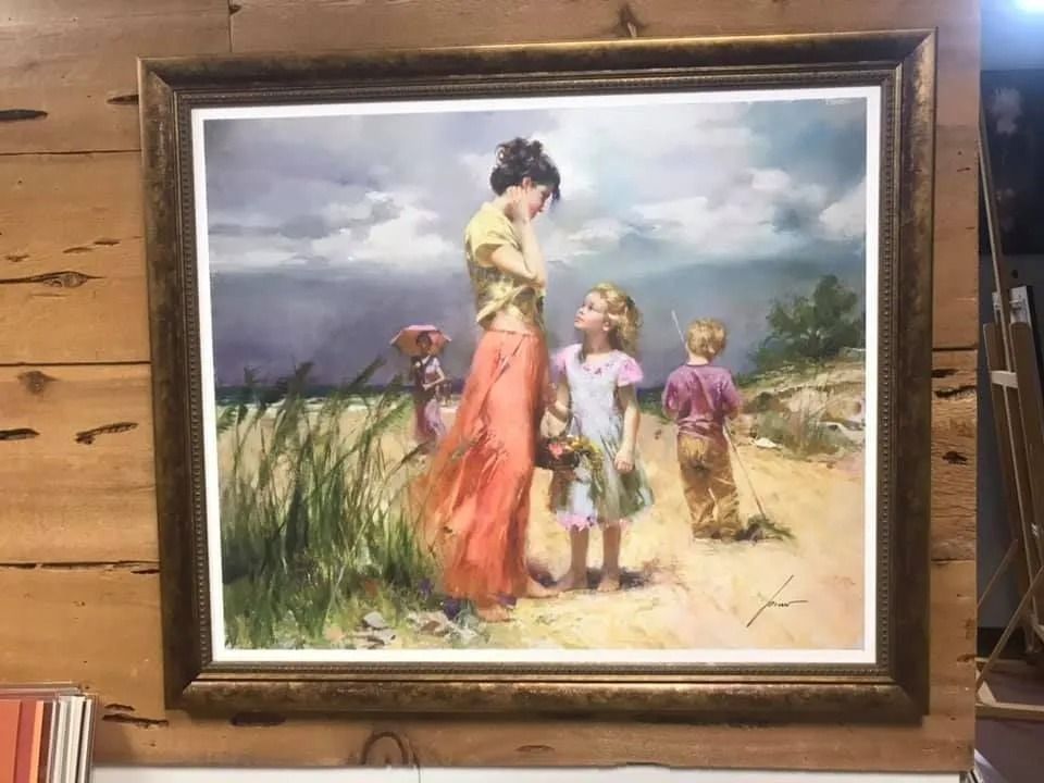 Framed painting of a woman with two children walking through sandy dunes near the beach