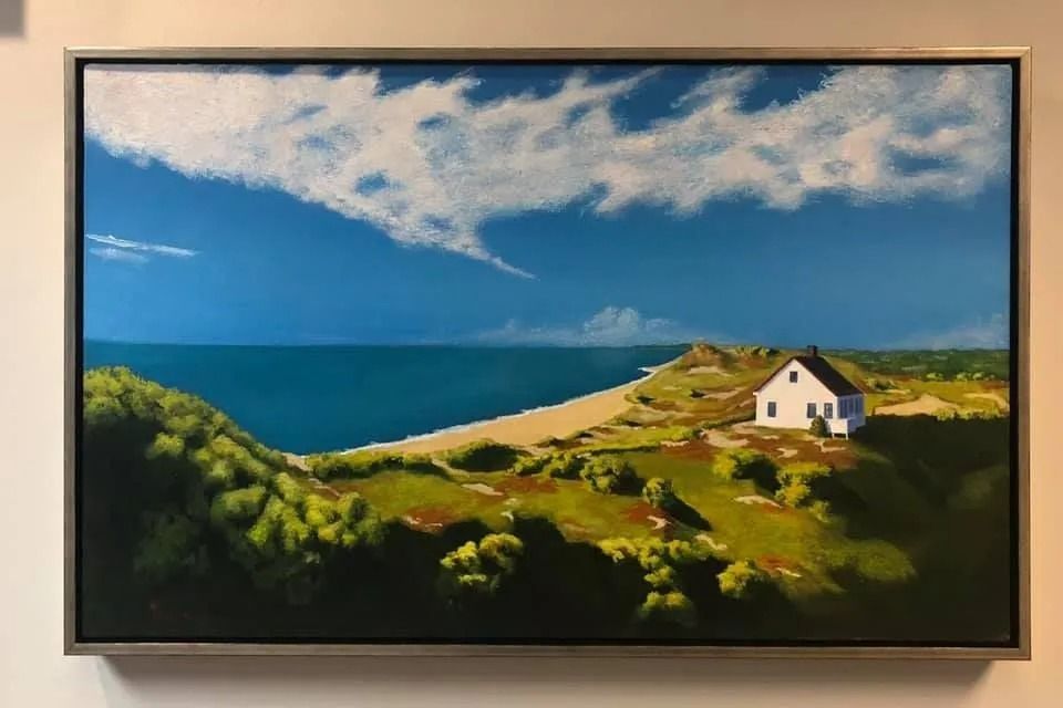 Coastal landscape painting with blue sea, sandy beach, green hills, and a small white house under a cloudy sky