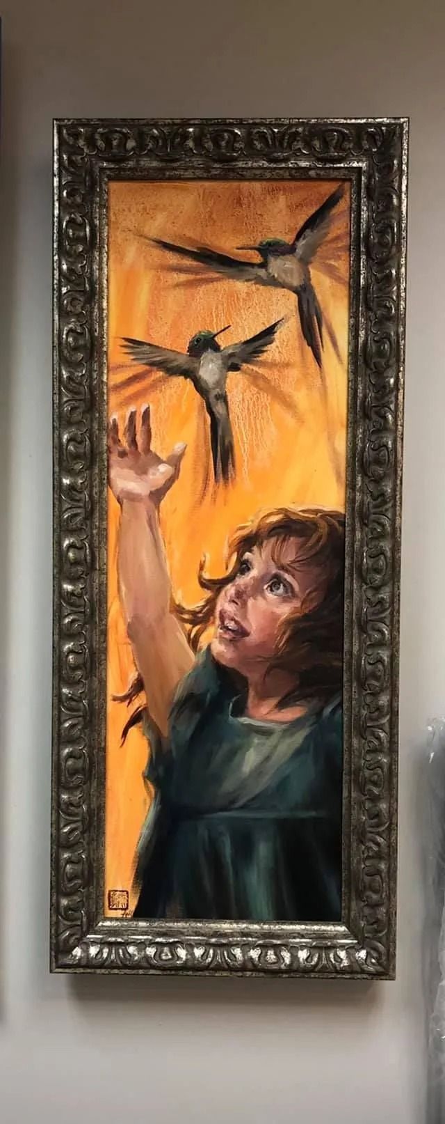 Framed painting of a woman reaching toward flying birds against an orange sky