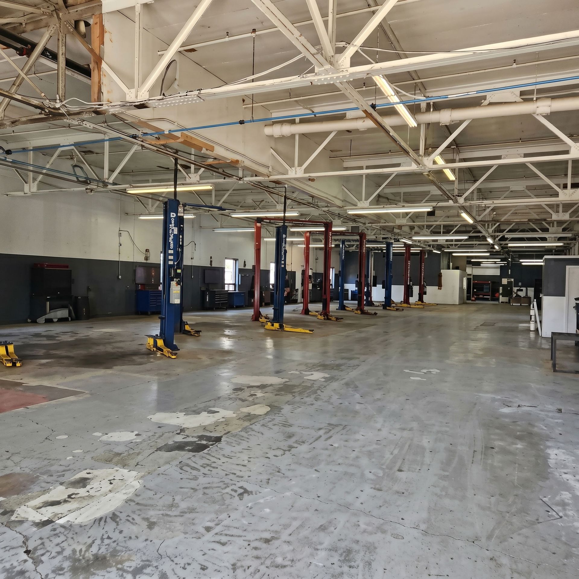 Intérieur vide d'un atelier automobile avec ponts élévateurs, poutres apparentes au plafond et sol en béton