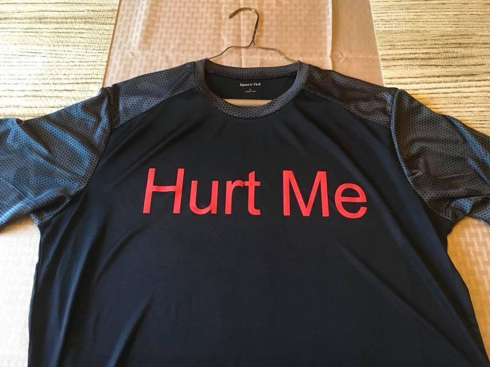 Black shirt on a hanger with red text reading “Hurt Me”