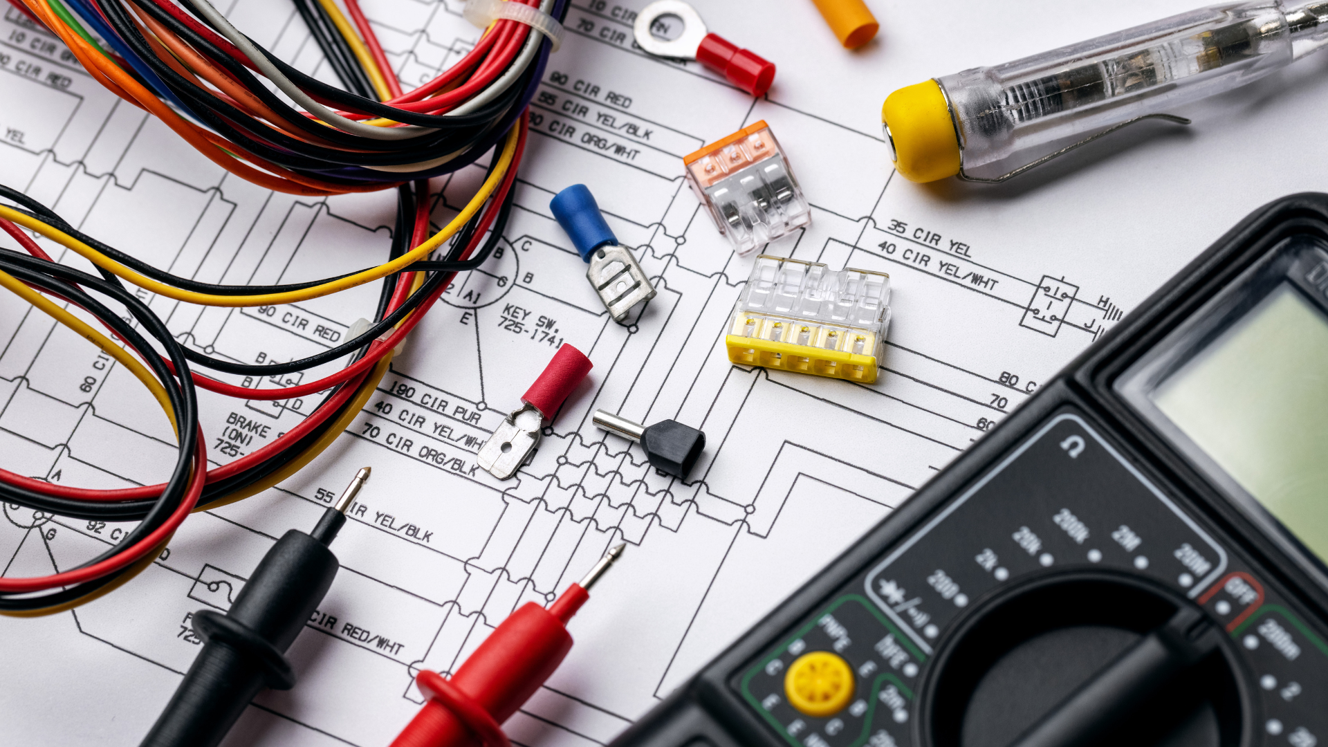 Electrical components, wires, and a multimeter placed on top of a technical circuit diagram.