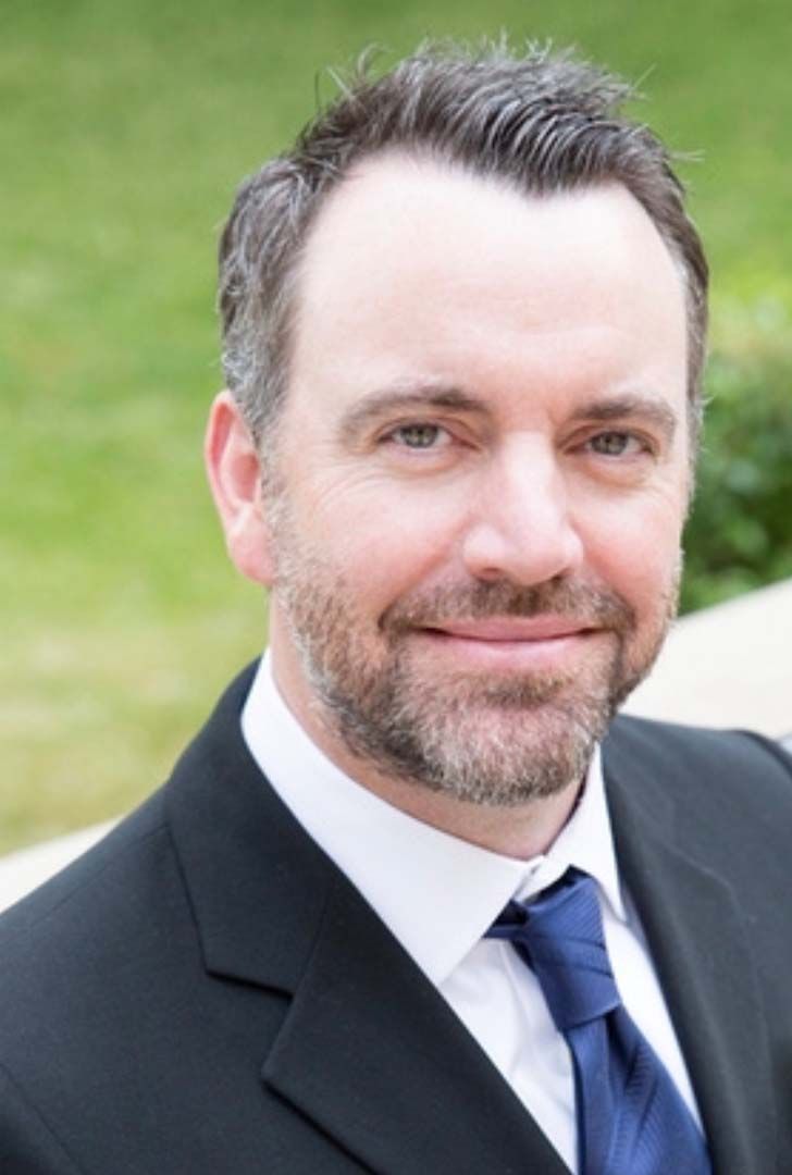 A man in a suit and tie is smiling for the camera.