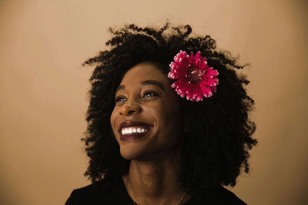 A woman with a flower in her hair is smiling.