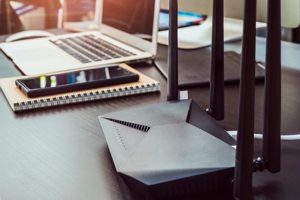 Black Wi-Fi Router with Antennas on A Desk Next to A Laptop — Oz Data Tech in Taree, NSW