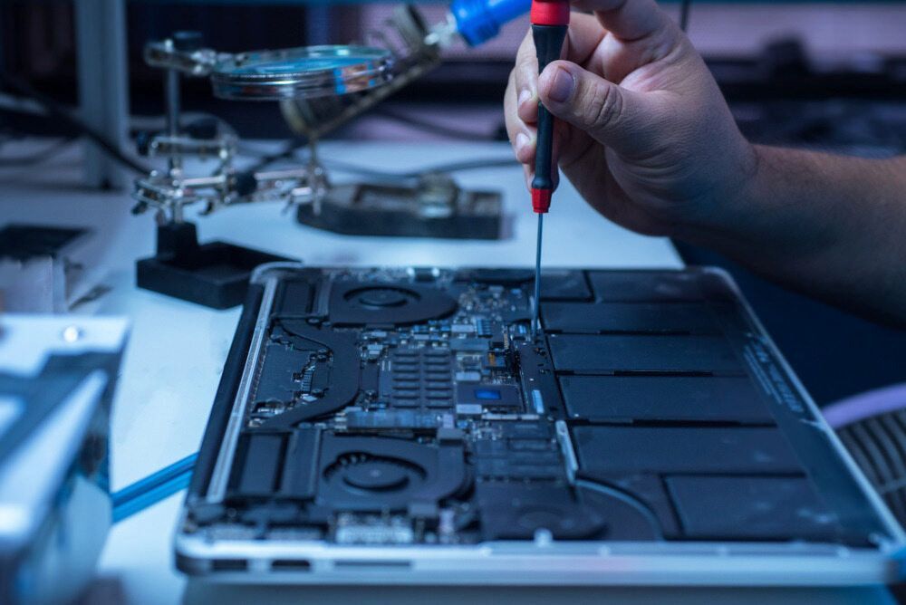 A Person Is Fixing A Laptop Computer With A Screwdriver — Oz Data Tech in Forster, NSW