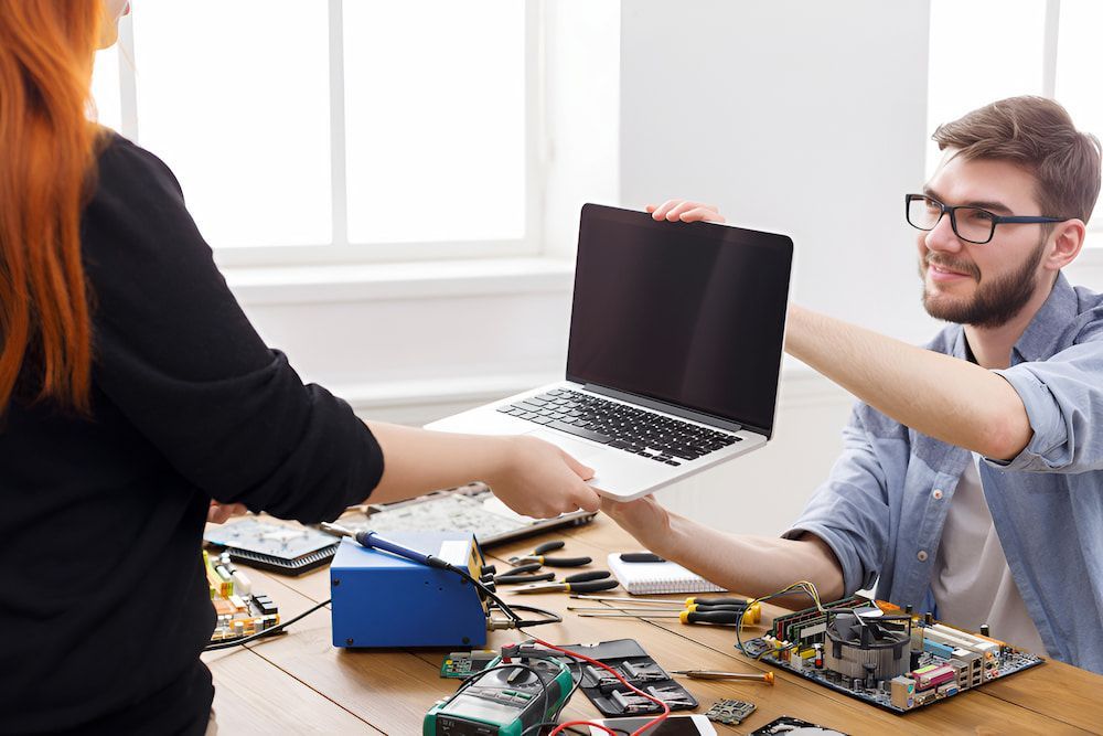 A Man And A Woman Are Working On A Laptop Computer — Oz Data Tech in Forster, NSW
