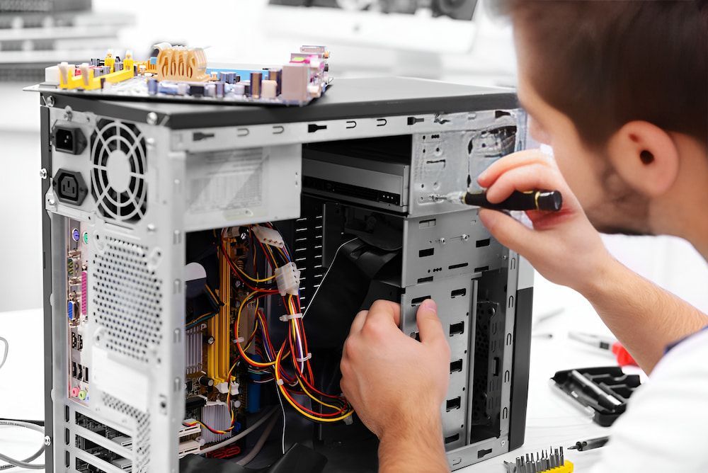 A Man Is Fixing A Computer With A Screwdriver — Oz Data Tech in Forster, NSW