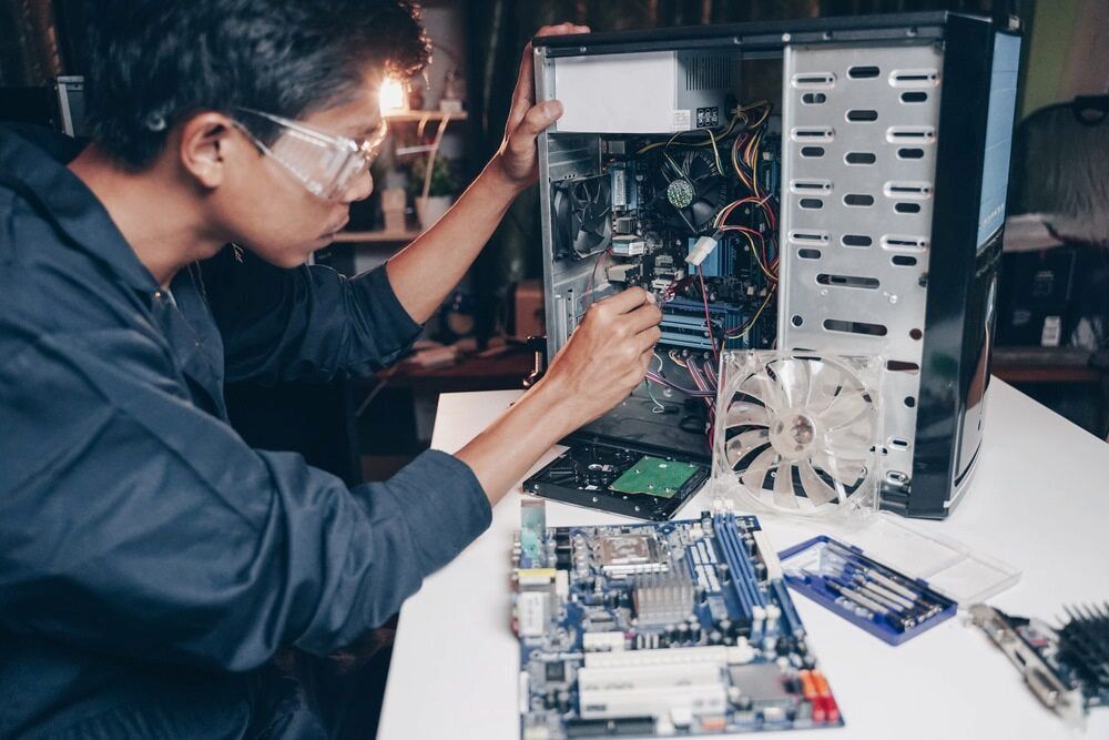 A Man Wearing Safety Glasses Is Working On A Computer — Oz Data Tech in Forster, NSW