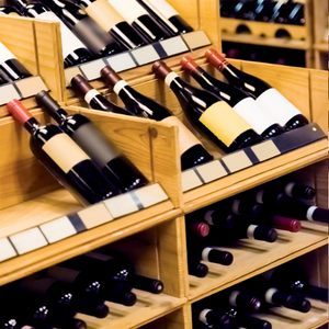 Wooden wine racks filled with bottles of red and white wine in a cellar.