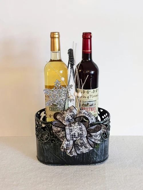 Two wine bottles in a black decorative gift basket with a silver bow