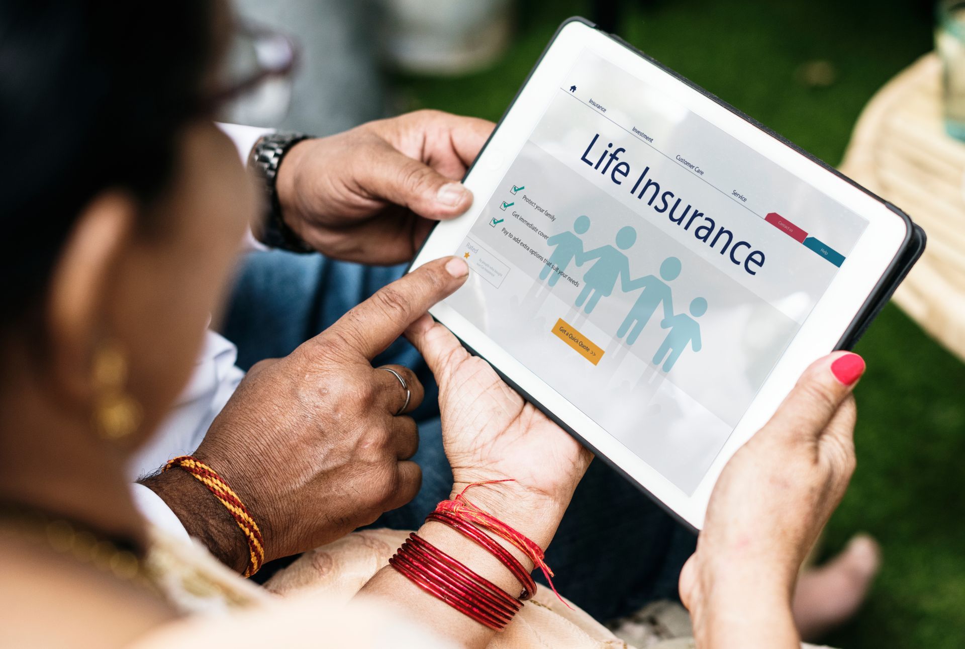 A couple reviewing life insurance policy options together on a tablet with family icons on screen