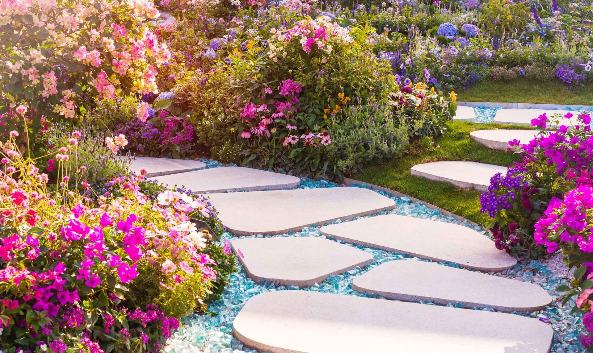 Curved stone garden path winding through lush pink and purple flowering bushes