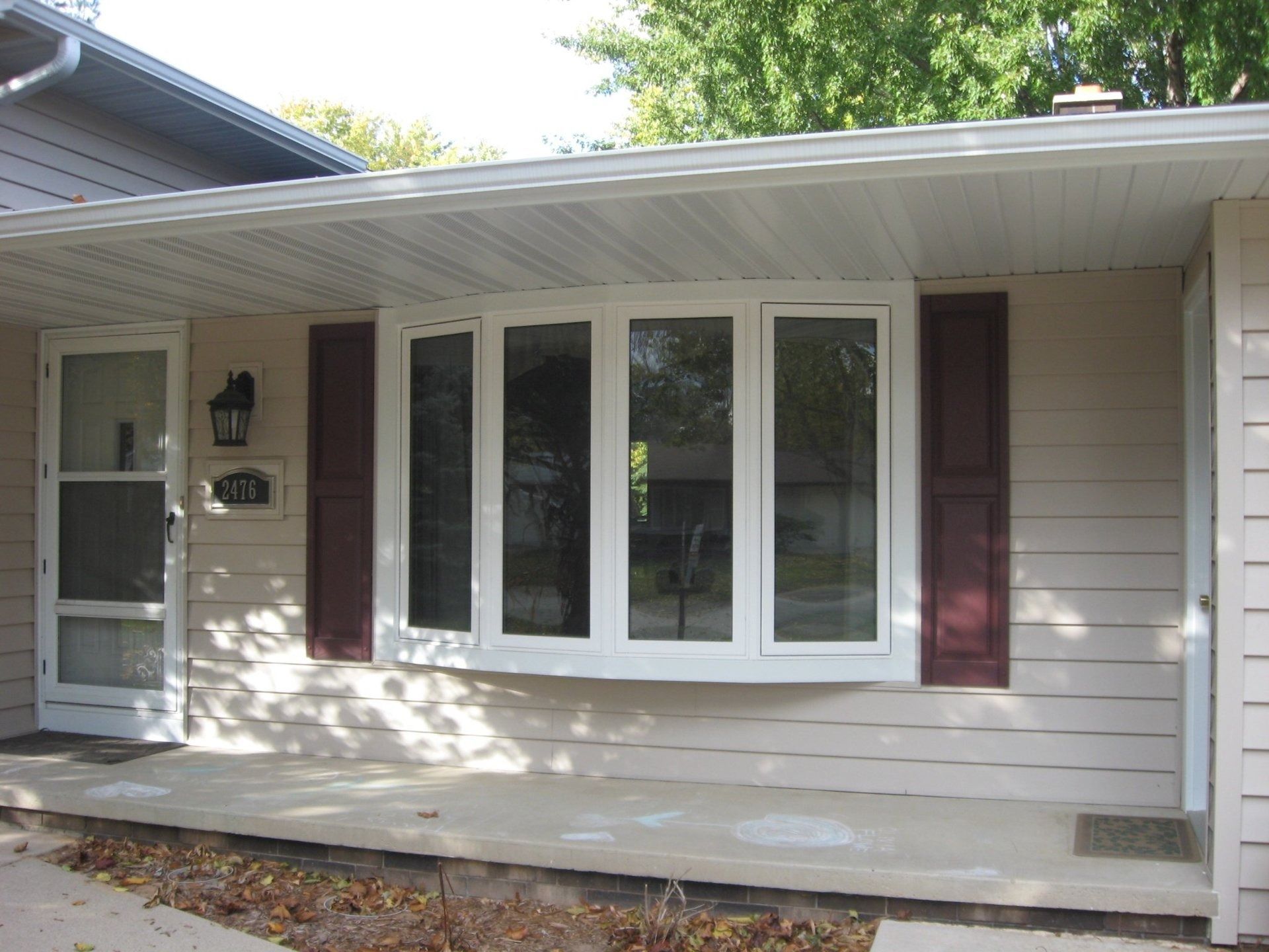 Front porch with white siding, large windows, and a covered entry on a house