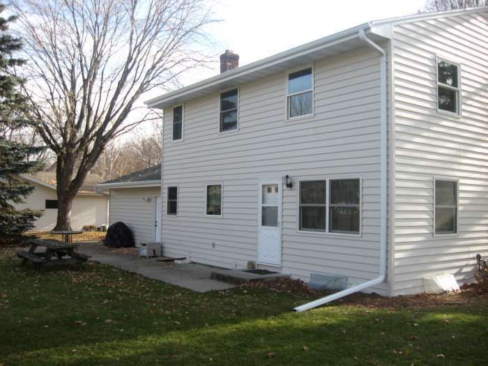 Two-story white house with a small yard, patio, and leafless trees outdoors.