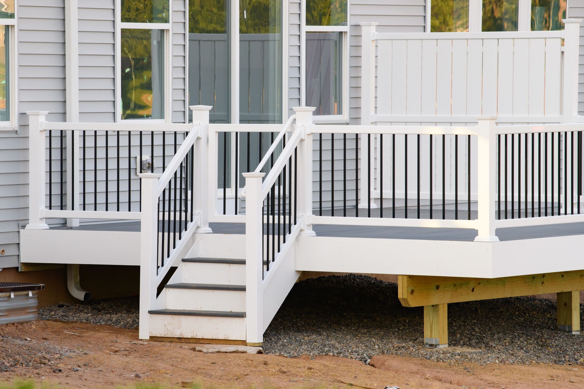 White porch steps and railing leading to a gray house entrance with a small deck.