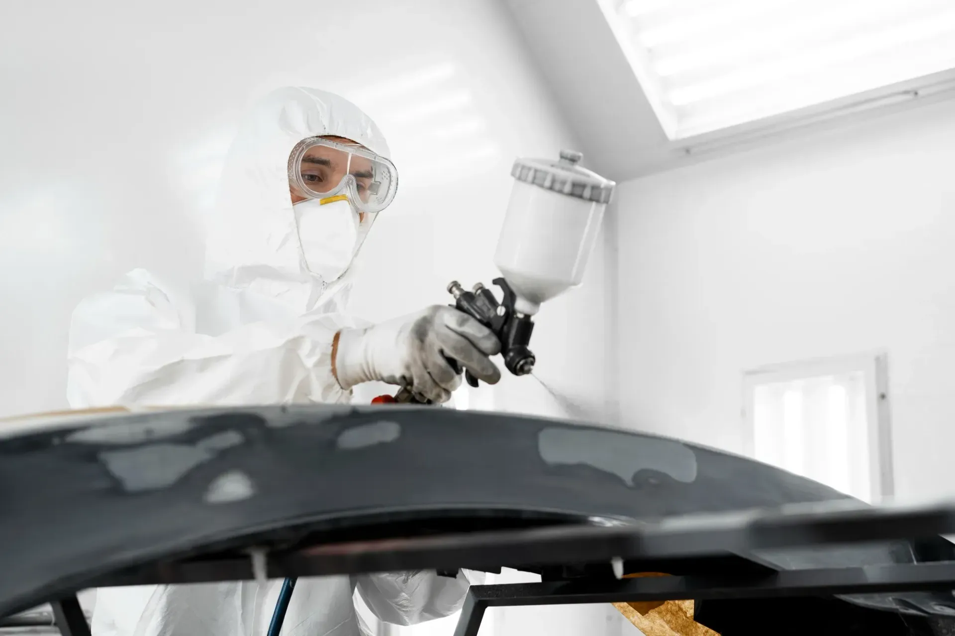 A man is spray painting a car in a paint booth. Located at Liverpool.