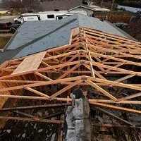 Partially reroofed house with exposed wooden trusses and new gray shingles on one side