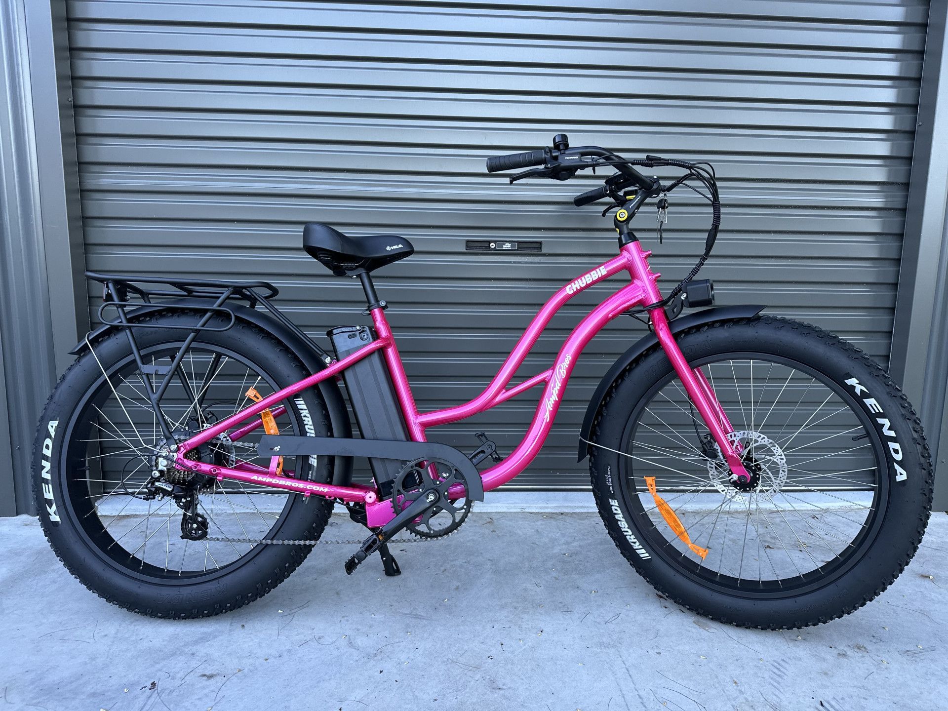 Pink electric fat tire bicycle parked in front of a gray shutter door — Grafton City Cycles in Grafton, NSW