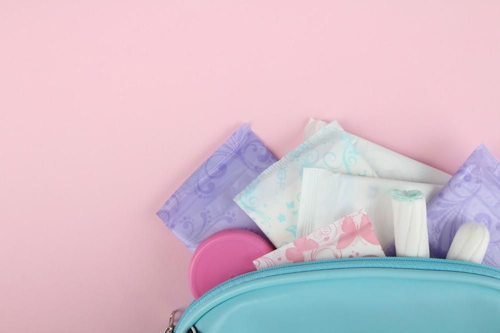 Diaper bag with baby diapers and wipes on a pink background
