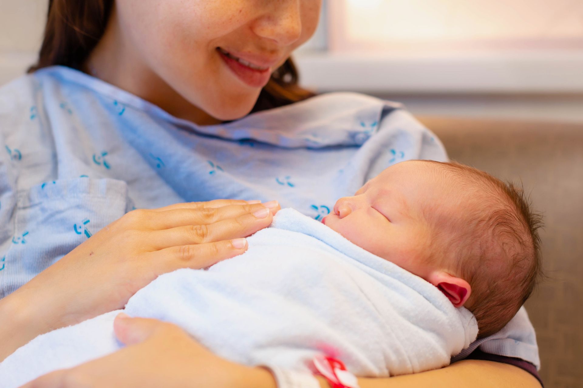 Woman cradling a sleeping baby wrapped in a white blanket