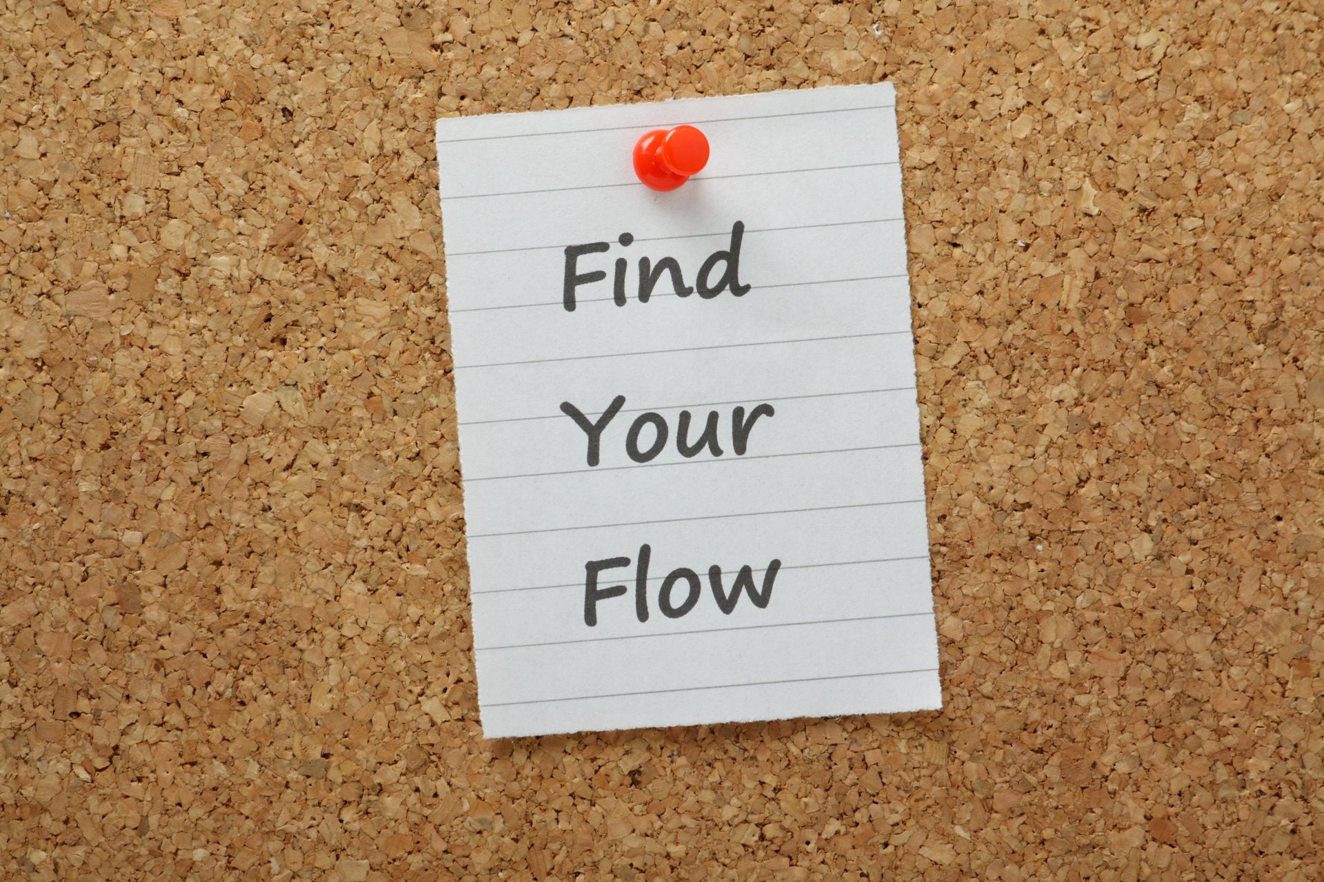 White note pinned to corkboard reading “Find Your Flow”