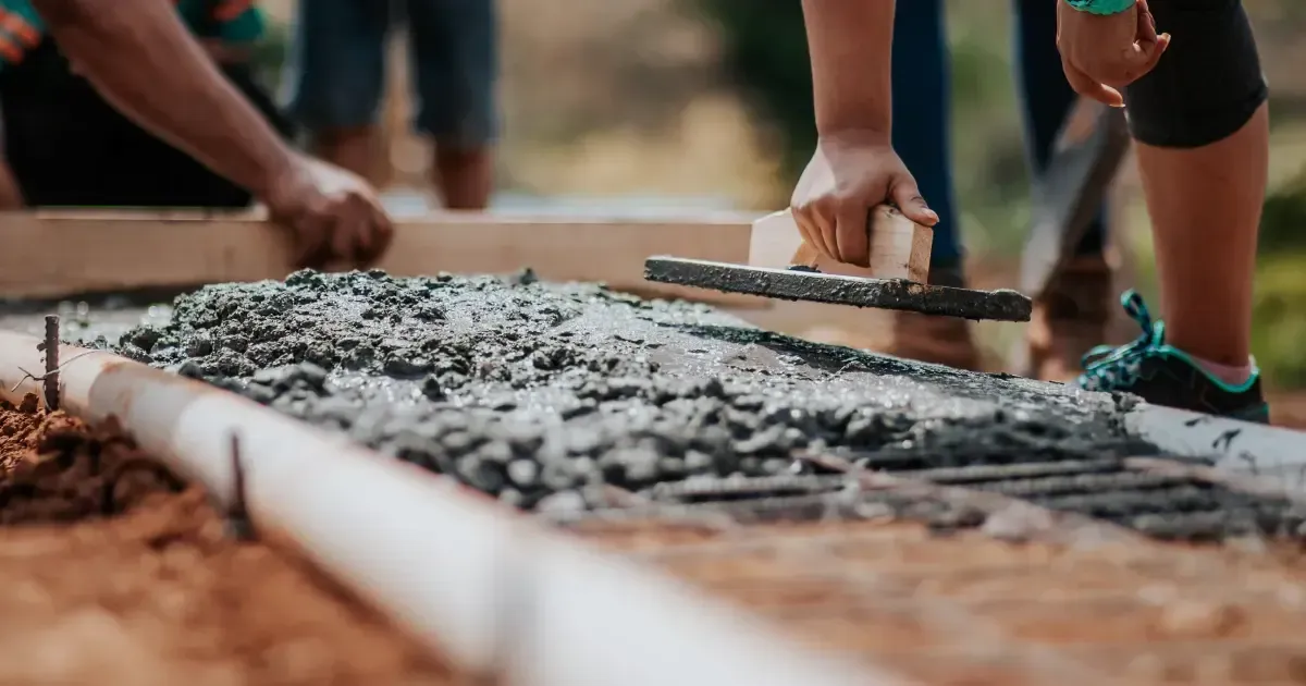 Hands leveling wet concrete with a trowel along a narrow form outdoors Hands leveling wet concrete with a trowel along a narrow form outdoors