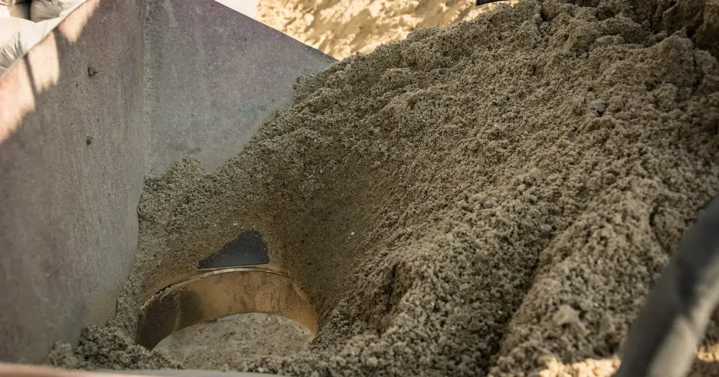 A large mound of sand or gravel in a metal container, with a shovel partly buried in it. A large mound of sand or gravel in a metal container, with a shovel partly buried in it.