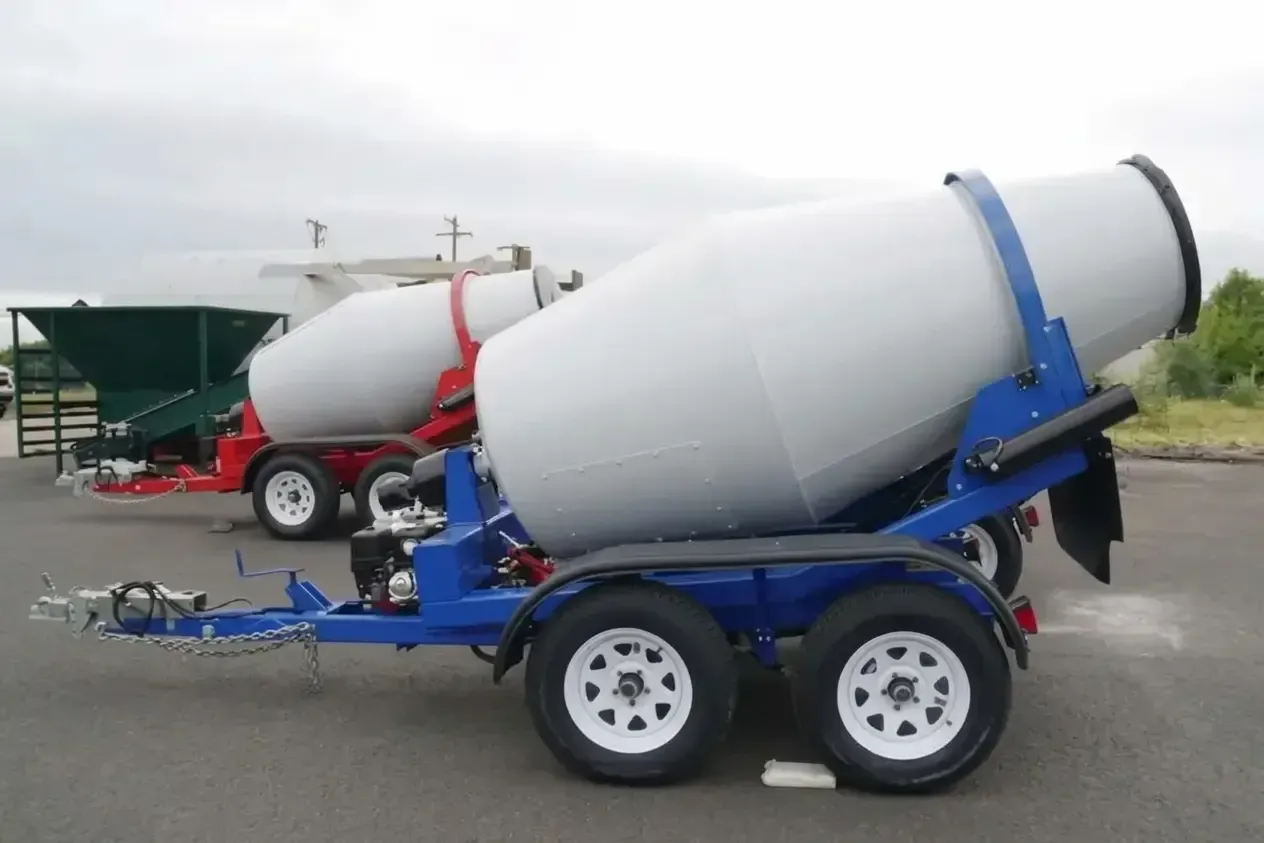 Concrete mixer truck on a blue trailer, with a second mixer truck in the background on a lot Concrete mixer truck on a blue trailer, with a second mixer truck in the background on a lot