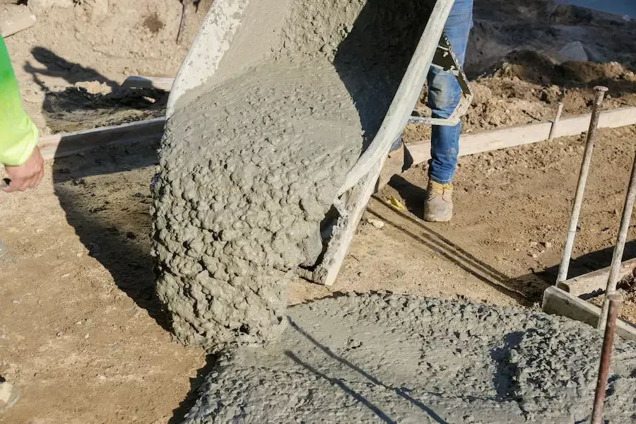 Wet concrete being poured from a chute at a construction site.