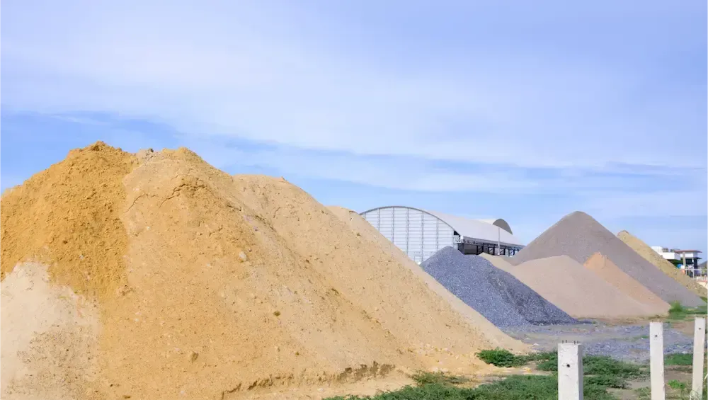Piles of sand and gravel at a construction site under a clear blue sky