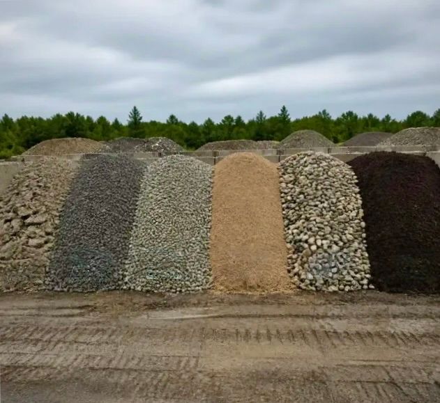 Row of gravel, sand, and topsoil piles with labels at a landscaping supply yard