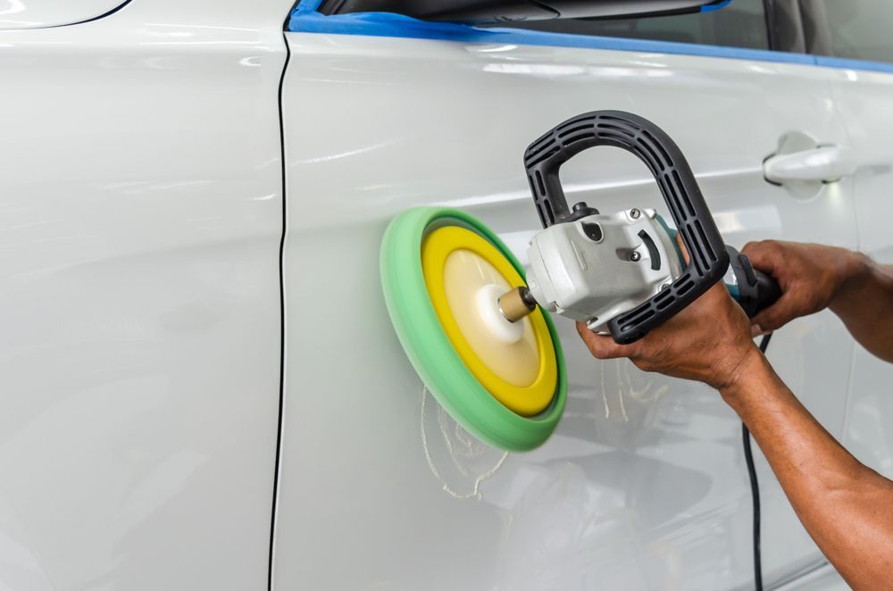 Person Polishing a White Car Door With a Green and Yellow Orbital Buffer — FNQ Paintless Dent Repair in Edmonton, QLD