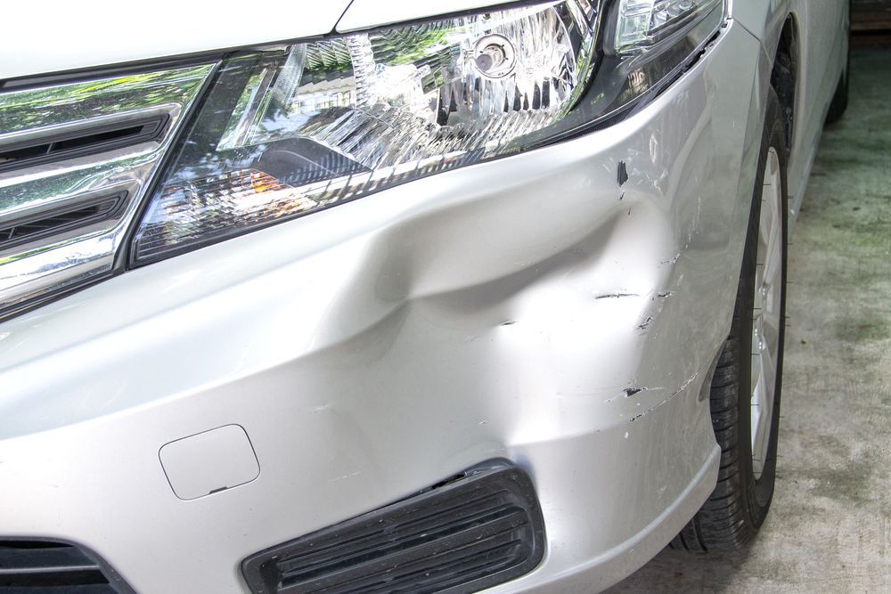 Silver Car Front Bumper With a Large Dent and Scratch Damage Near the Headlight — FNQ Paintless Dent Repair in Edmonton, QLD