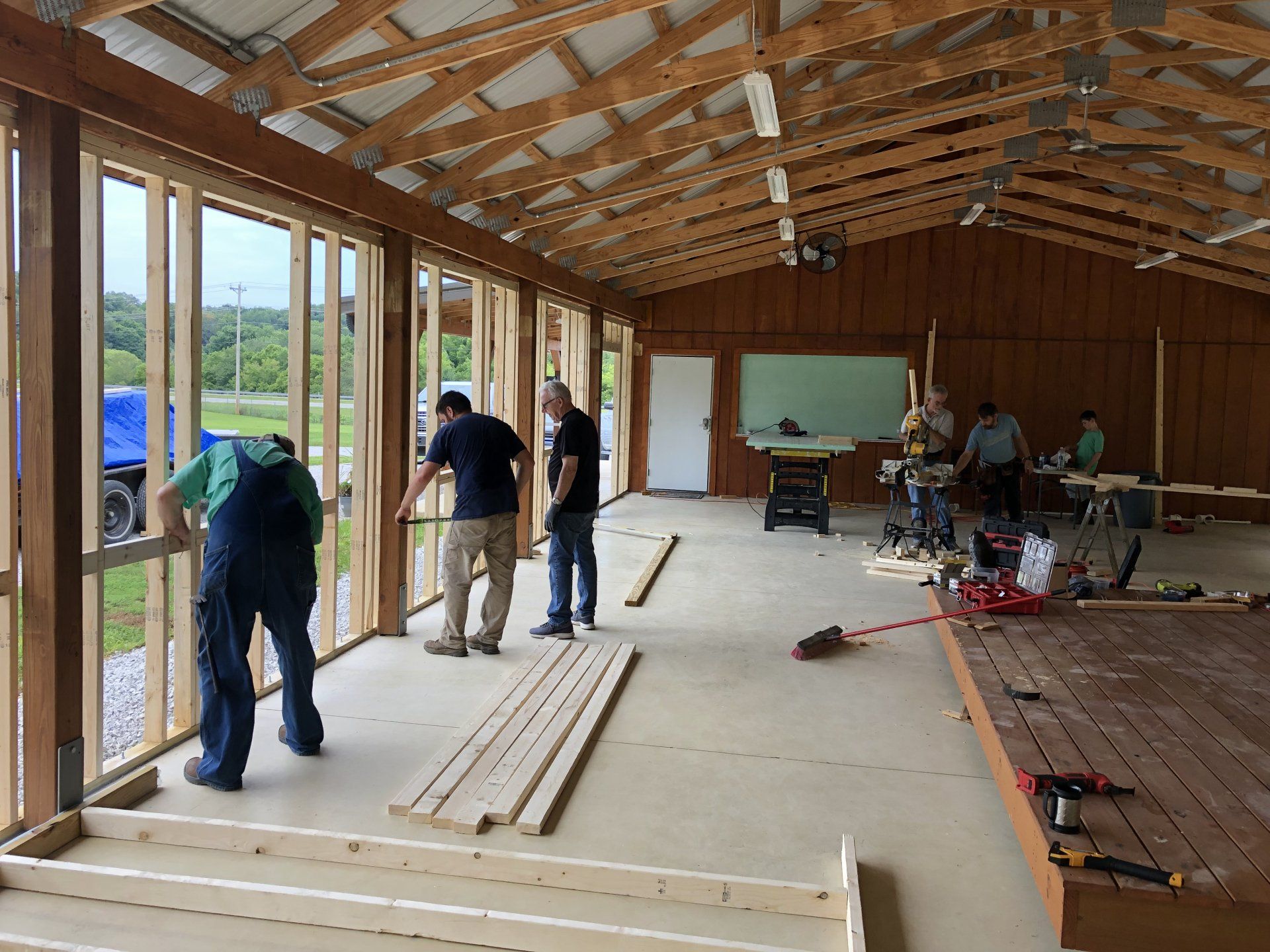 People building a wooden structure. Men constructing walls, with tools and materials. Interior view.