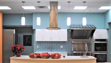 Kitchen with white cabinets, blue backsplash, stainless steel appliances, and island with food.