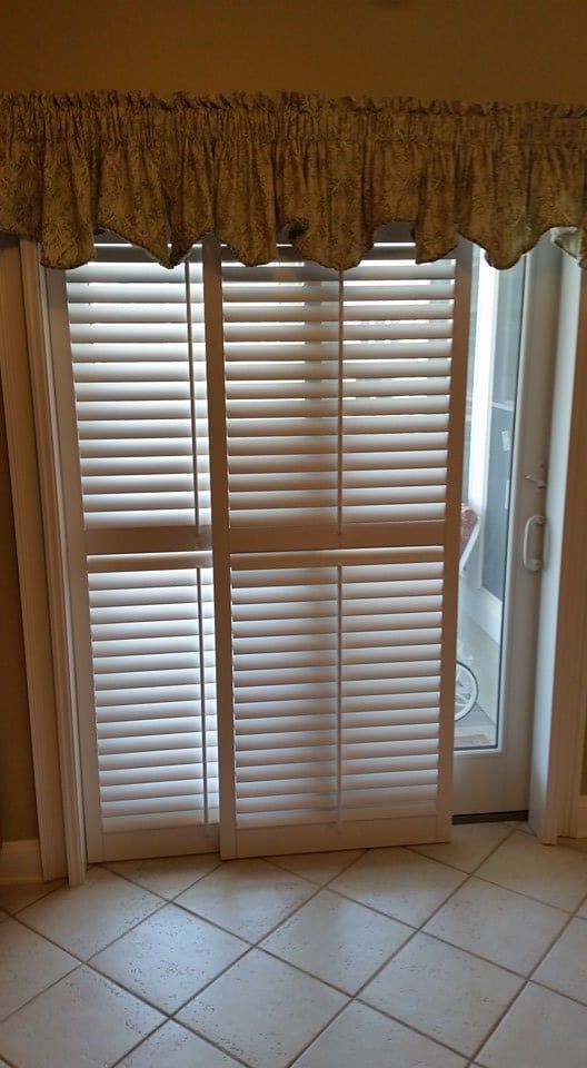 There is a sliding glass door with shutters on it.