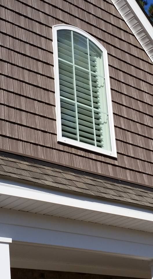 A window on the side of a house with shutters on it.