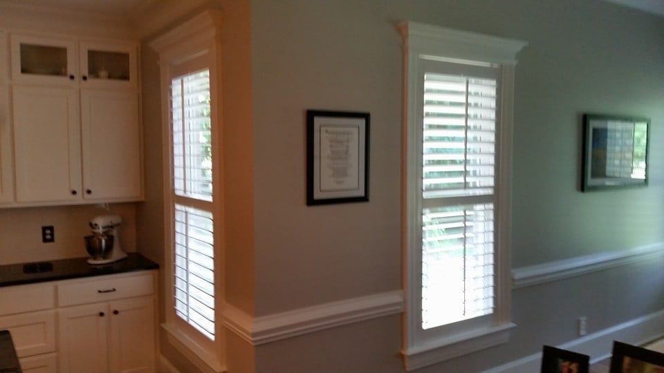 A kitchen and a dining room with shutters on the windows