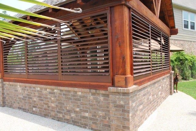 Wooden shudders on outdoor structure with brick base and louvered walls, brown roof, and lush green lawn in Washington, NC.