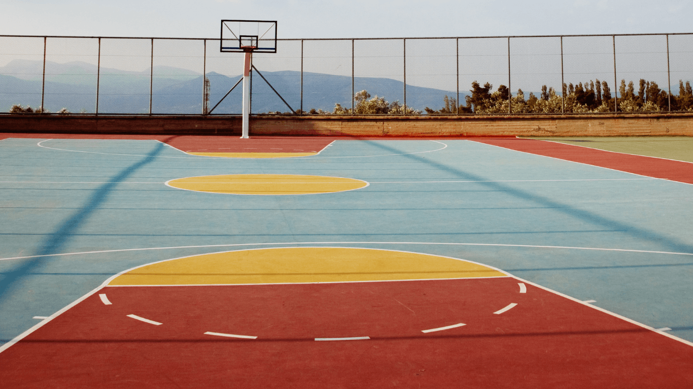 Newly painted basketball court with bright red, blue, and yellow sections and crisp lines after a court installation service in Chandler, AZ