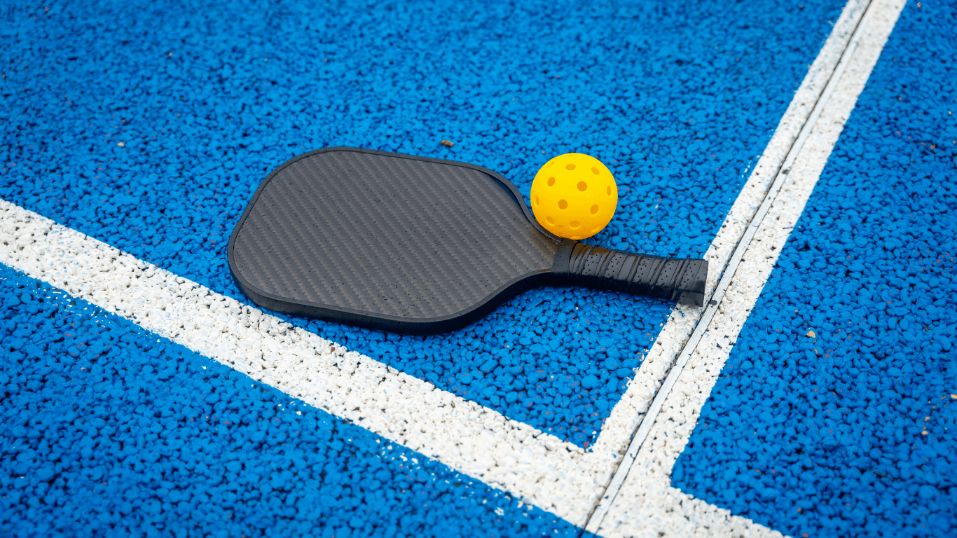 Pickleball paddle and yellow ball resting on a blue textured court with white lines during a court installation service in Chandler, AZ
