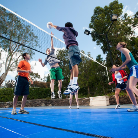 Group of kids jumping and playing volleyball on a bright outdoor court during a court installation service in Chandler, AZ